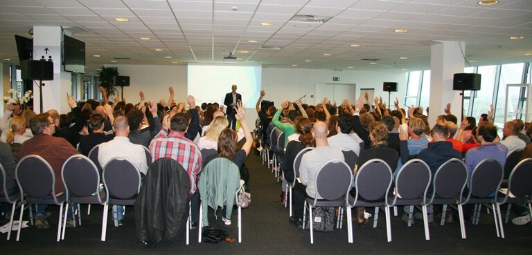 gevulde zaal met dagvoorzitter